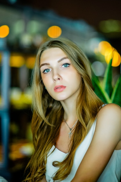 Girl with blue eyes sitting on urban cafe. woman with brown wavy hairstyle.