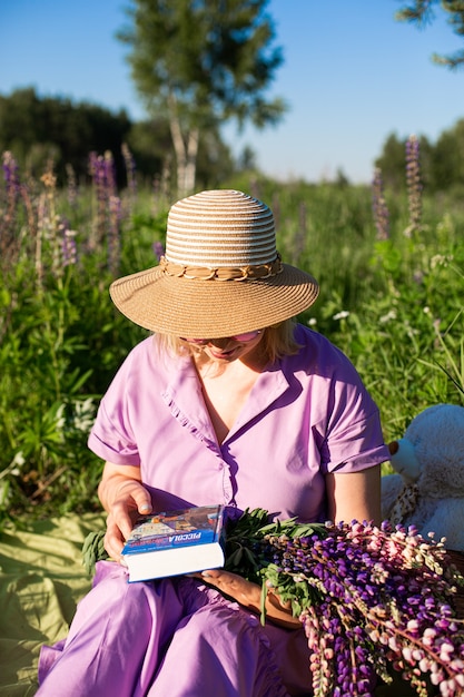 a girl with book in a blooming field in the sun at sunset