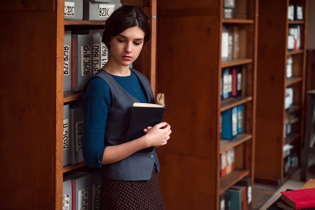 学校の図書館で手に本を持つ少女。