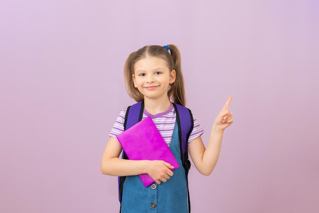 A girl with a book in her hands points her finger at your\
advertisement. a schoolgirl with a book on an isolated\
background.