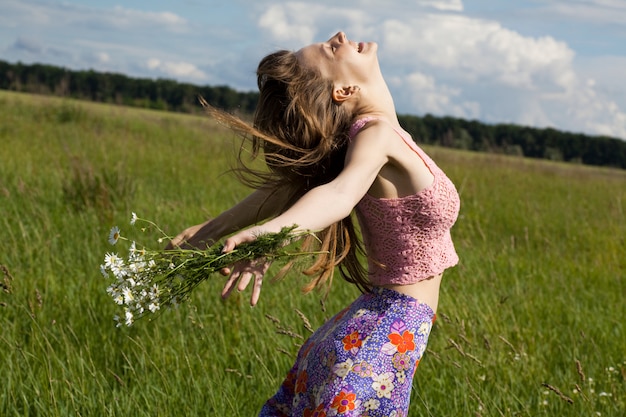 Girl with a bouquet of daisies in a field