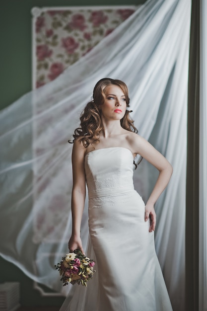 The girl with a bouquet at a developing curtain