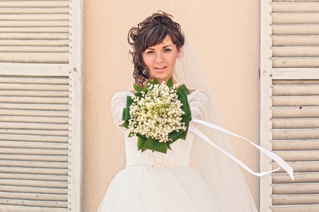 Ragazza con un mazzo di fiori in piedi al muro