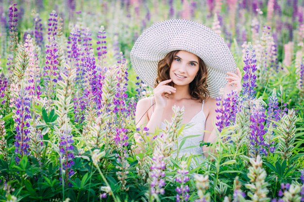 Girl with a bouquet of lupine on the field