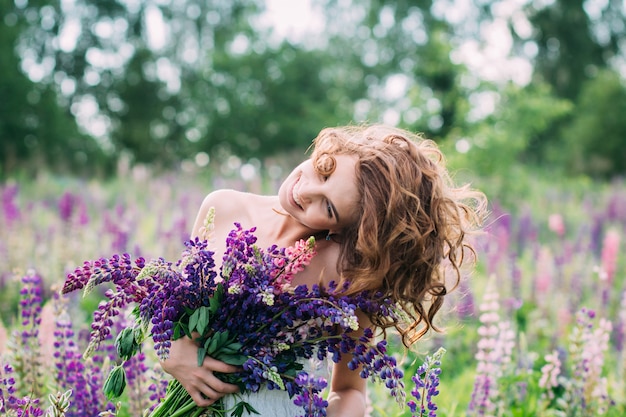 Girl with a bouquet of lupine on the field