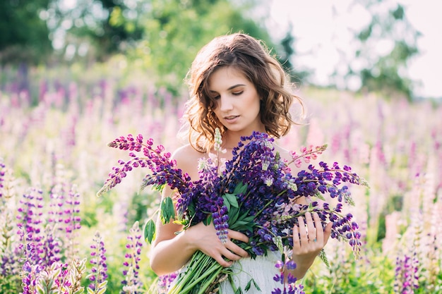 Girl with a bouquet of lupine on the field