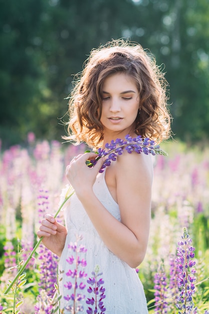 Girl with a bouquet of lupine on the field