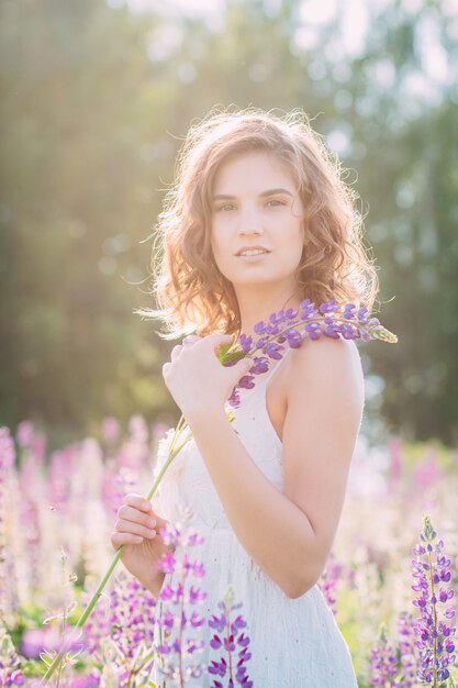 Girl with a bouquet of lupine on the field