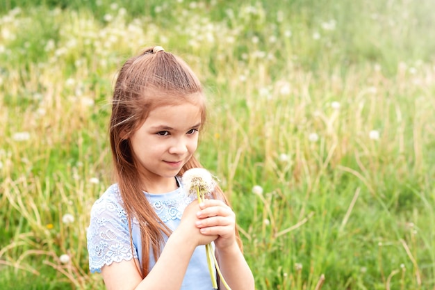 Girl with a bouquet of white dandelions and flying seeds