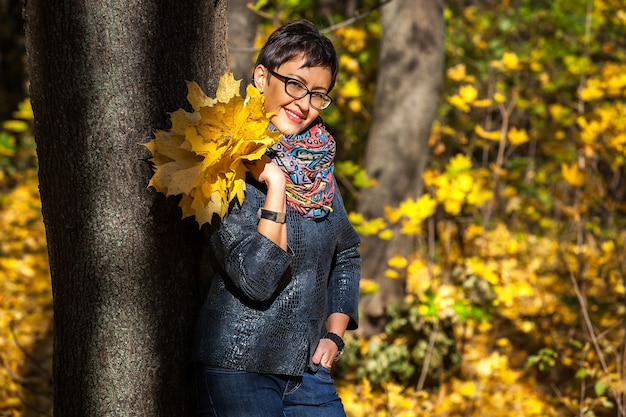 Girl with a bouquet of yellow leaves in the park a bouquet of yellow leaves fallen leaves