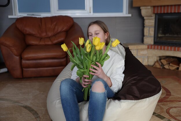 Girl with a bouquet of yellow tulips in the room