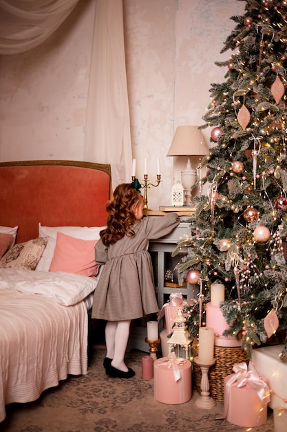 A girl with a bow on her head at home near the Christmas tree