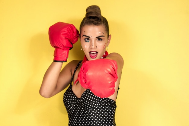 Girl with boxing gloves POP ART retro make up style isolated on yellow
