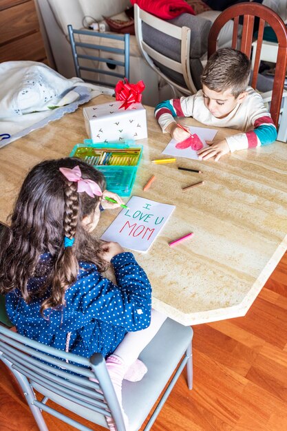 写真 テーブルでグリーティングカードを作っている弟の女の子