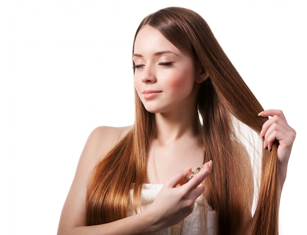 Girl with brown hair spraying perfume on her wrist