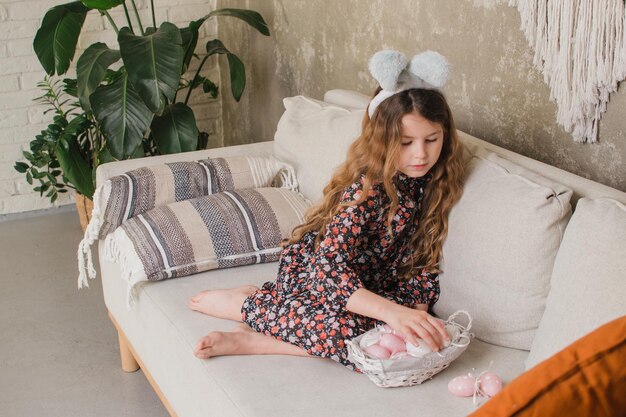 Girl with bunny ears putting eggs in a basket