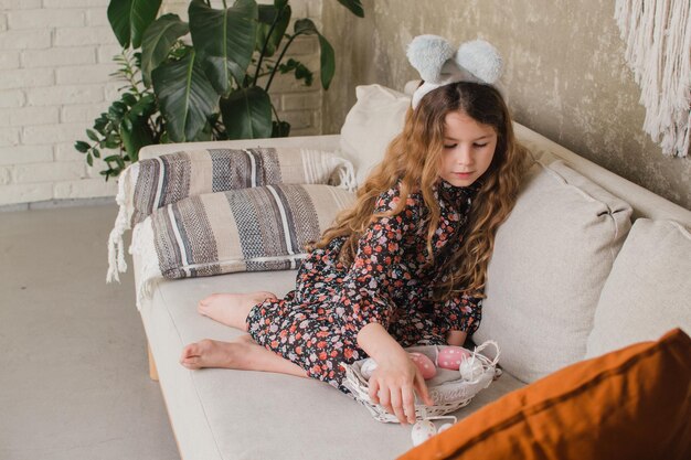 Girl with bunny ears putting eggs in a basket