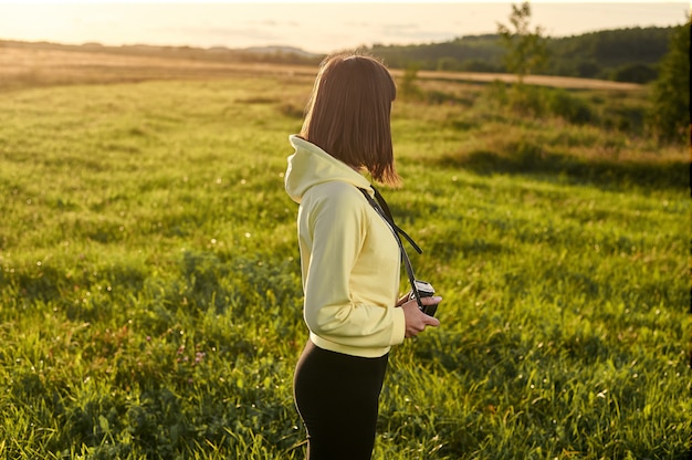 A girl with a camera is preparing to shoot the dawn on an early summer morning.