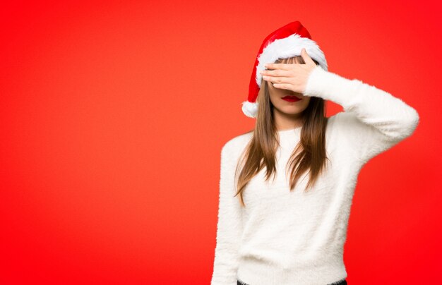 Girl with celebrating the christmas holidays covering eyes by hands