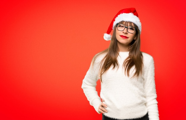 Girl with celebrating the christmas holidays posing with arms at hip and smiling on red background