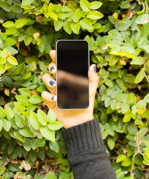 Foto ragazza con un telefono cellulare su uno sfondo di fogliame