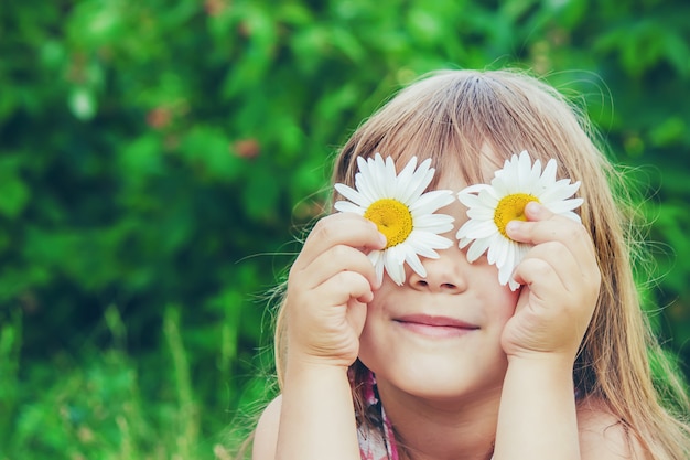 Ragazza con camomilla messa a fuoco selettiva i fiori della natura