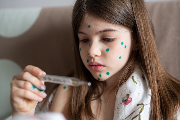 a girl with chickenpox measures her temperature