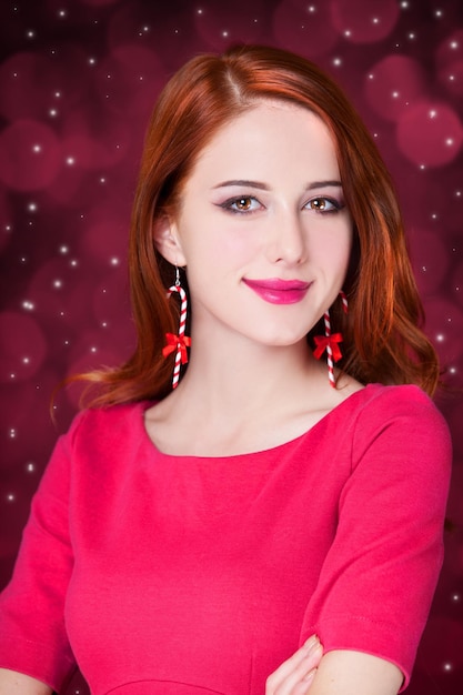 Girl with christmas earrings on red background isolated