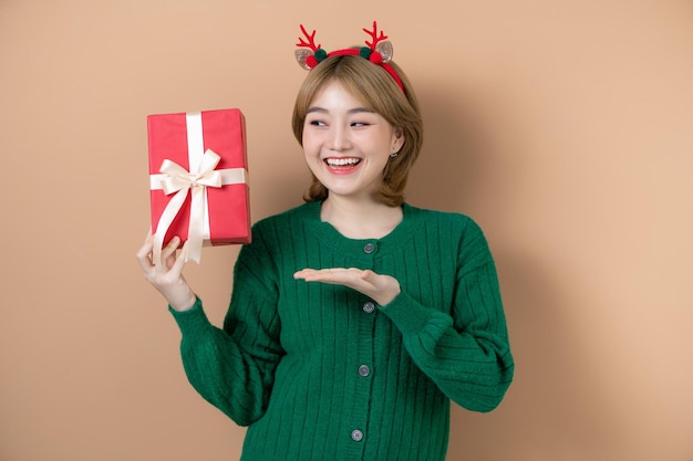 孤立したベージュの背景にクリスマスの帽子を持つ少女