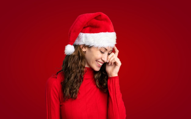 Girl with christmas hat over isolated yellow wall laughing