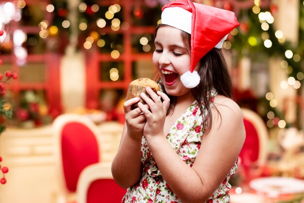 Girl with christmas hat and little panettone, christmas background