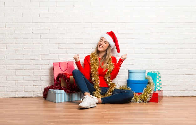 Girl with christmas hat and many gifts celebrating the christmas holidays celebrating a victory