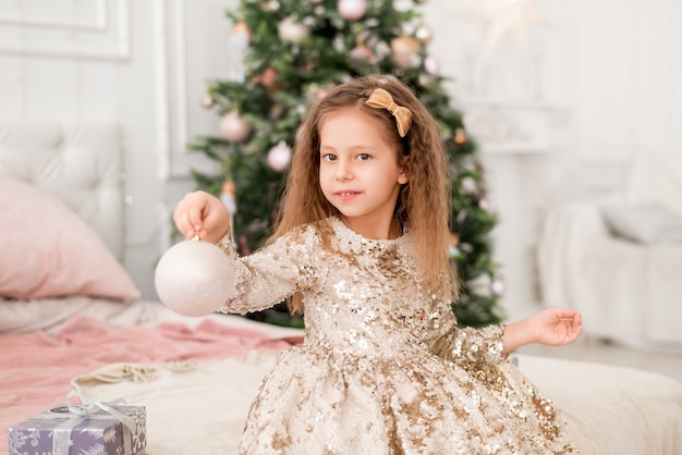 그녀의 손에 크리스마스 장난감을 가진 소녀입니다. 크리스마스 공을 든 아이의 초상화