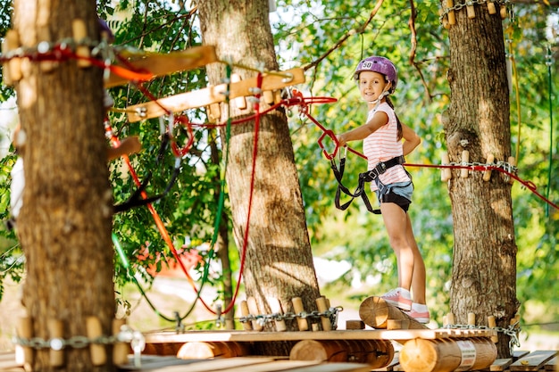 Girl with climbing gear in an adventure park are engaged in
rock climbing or pass obstacles on the rope road