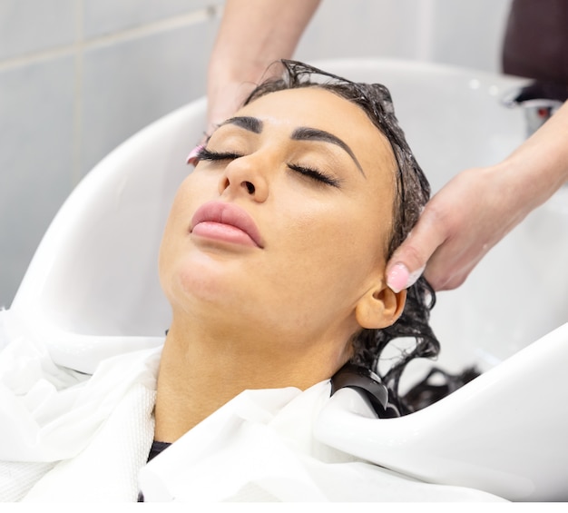 Girl with closed eyes washes her hair in beauty salon