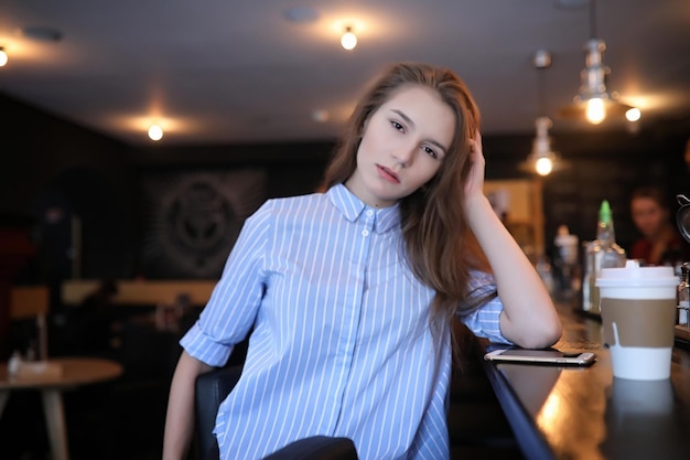 Girl with coffee Young beautiful girl is sitting in a cafe and drinking coffee