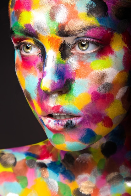 Girl with colored face painted. Art beauty image.