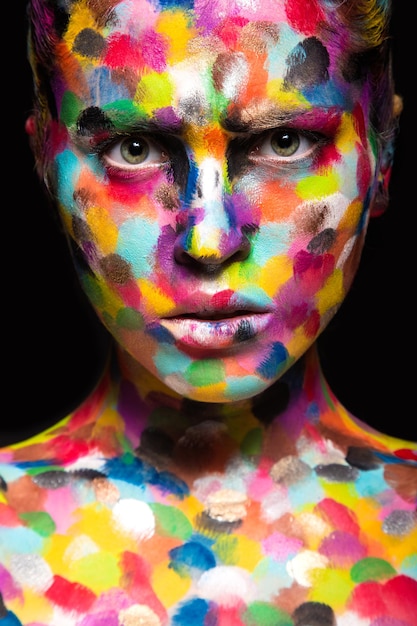 Girl with colored face painted. Art beauty image.