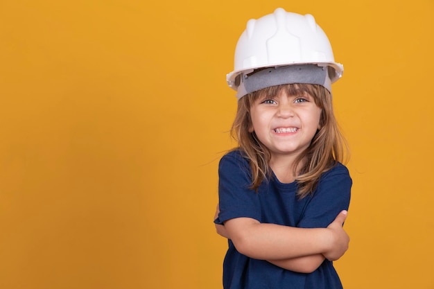 건설 도구를 가진 소녀 안전 헬멧과 어린이 보호를 가진 소녀 건축가가 되기를 꿈꾸는 귀여운 소녀 텍스트를 위한 여유 공간과 함께 웃고 있는