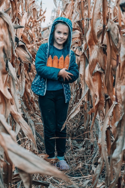 背景をぼかした写真の手でトウモロコシの穂軸を持つ少女