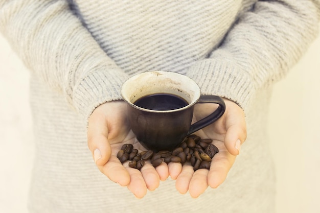 Girl with cup and coffee beans in hands