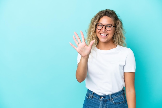 Girl with curly hair isolated on blue background counting five with fingers