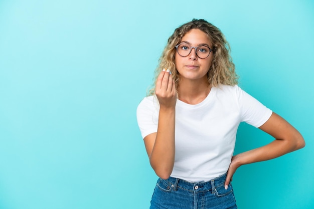 Girl with curly hair isolated on blue background making Italian gesture