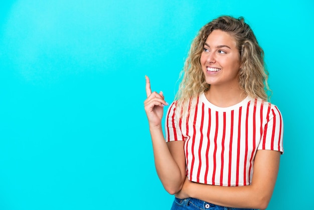 Photo girl with curly hair isolated on blue background pointing up a great idea