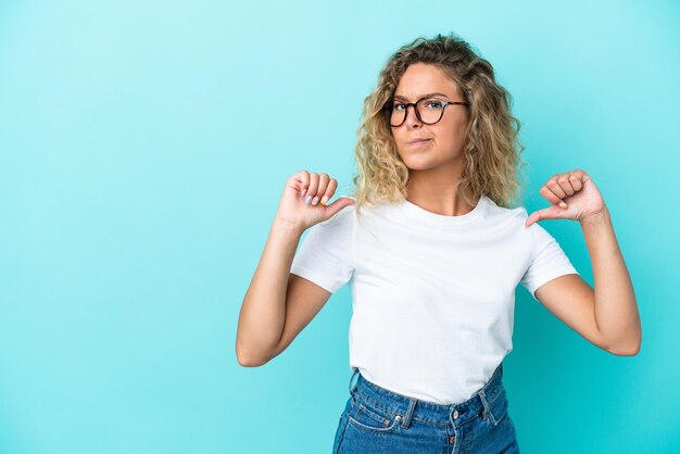 Girl with curly hair isolated on blue background proud and selfsatisfied