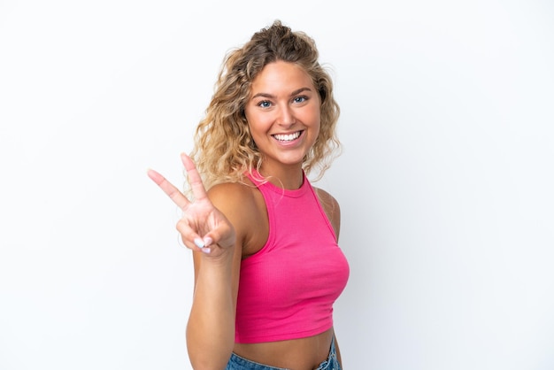 Girl with curly hair isolated on white background smiling and showing victory sign