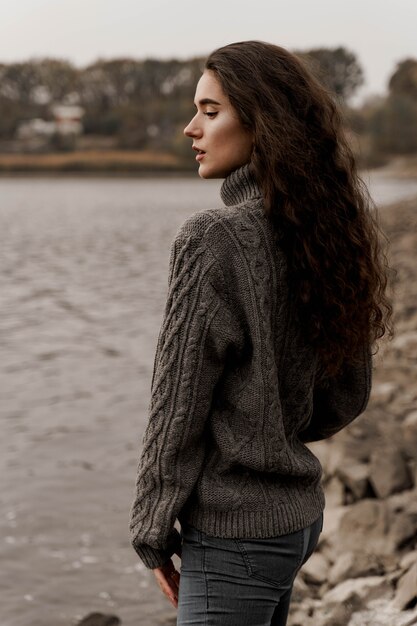 Ragazza con capelli ricci vicino al lago in autunno