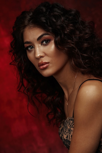 A girl with curly hair poses on a dark background