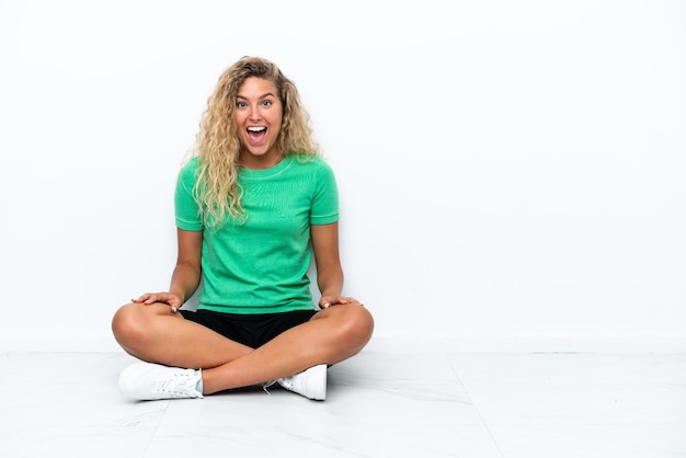 Girl with curly hair sitting on the floor with surprise facial expression