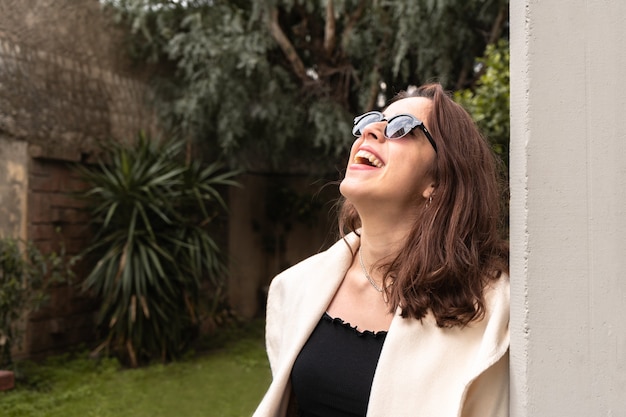 Girl with dark sunglasses looking up and laughing